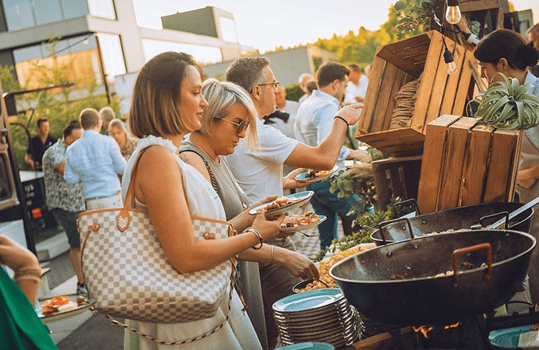 Gasten scheppen eten op bij een buitenbuffet tijdens een zomeravondevent bij DD2